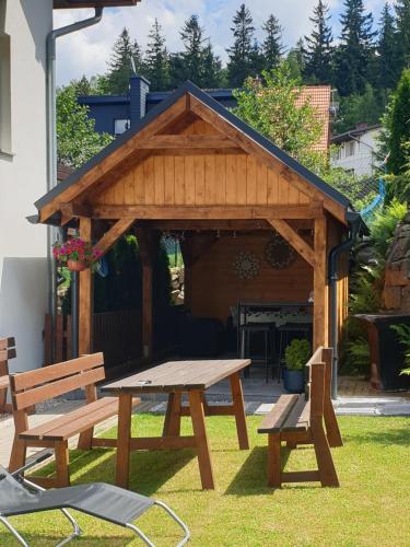 a wooden picnic table and benches in a yard at VILLA MILA Apartamenty in Karpacz