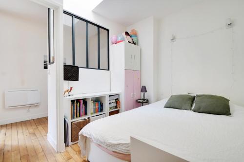- une chambre blanche avec un lit et une étagère dans l'établissement GuestReady - Modern Comfort near Montparnasse, à Paris