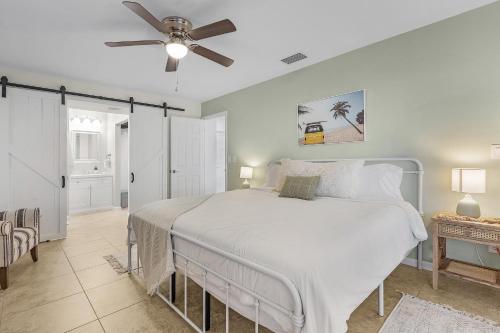 a bedroom with a white bed with a ceiling fan at Cozy Retreat, heated pool, water canal, bikes,3 bedroom in Cape Coral