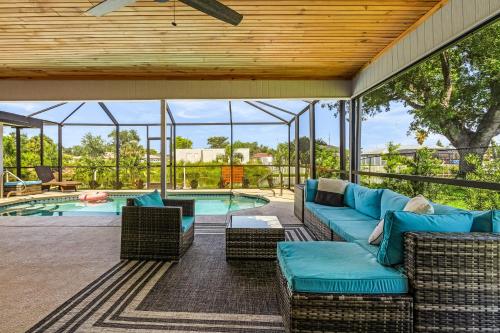 an outdoor patio with a couch and chairs next to a pool at Cozy Retreat, heated pool, water canal, bikes,3 bedroom in Cape Coral