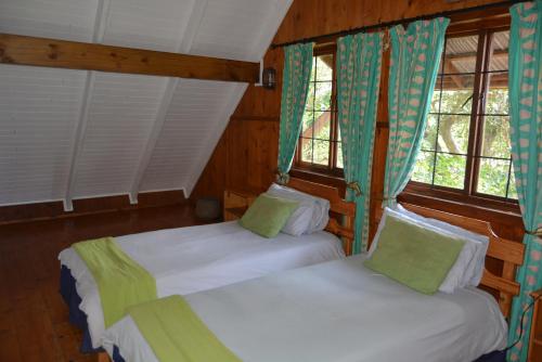 two beds in a room with two windows at House 52 in Sodwana Bay