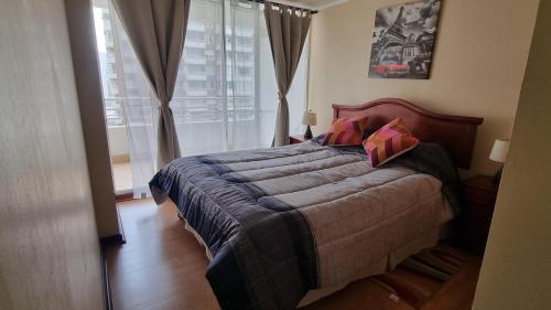 um quarto com uma cama grande e almofadas cor-de-rosa em Departamento central, 2 Dormitorios 4 personas em Viña del Mar