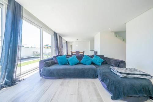 un soggiorno con un grande divano blu con cuscini blu di Black Pool House just 10 minutes away from the beach a Amora