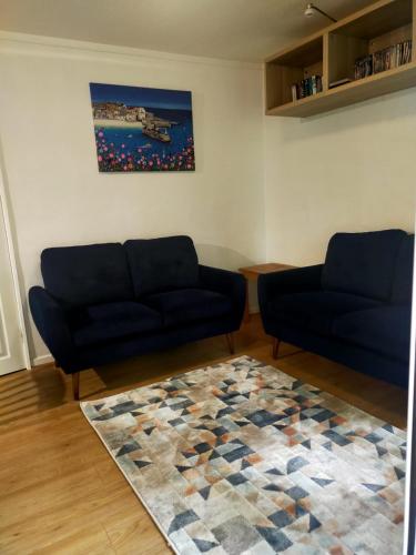 a living room with two blue couches and a rug at Woodland View - Families & Pets in Uny Lelant