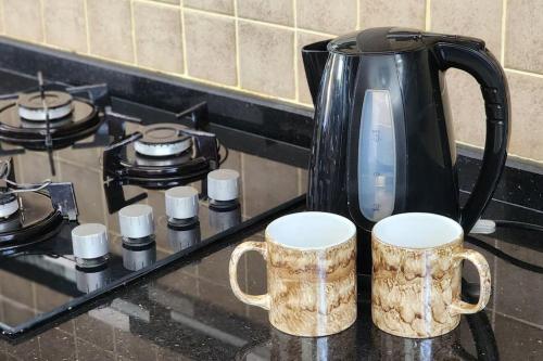 a coffee pot sitting on top of a stove with two mugs at 3 bedroom bungalow in Alsancak in Kérynia
