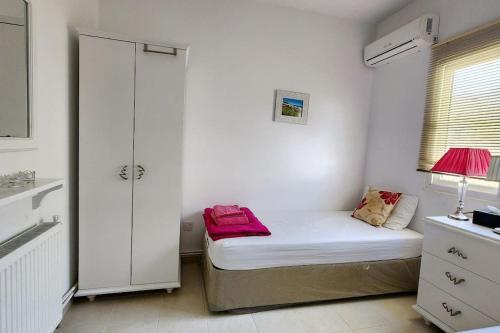 a small white room with a bed and a window at 3 bedroom bungalow in Alsancak in Kérynia