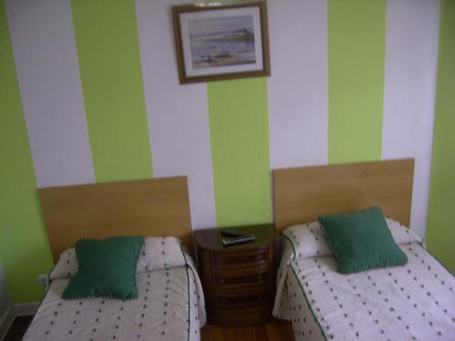 two beds in a room with green and white stripes at Pensión Gema in Irún