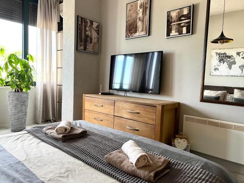 a bedroom with a television and towels on a bed at Panama apartment in Ulcinj