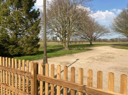 a wooden fence with a telephone pole next to a dirt road at The Old Dairy & The Old Stables in Thetford