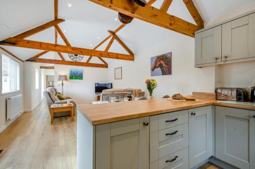 a kitchen with white cabinets and wooden beams at The Old Dairy & The Old Stables in Thetford