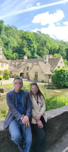 a man and a woman sitting on a stone bench at Relax and unwind at Windrush Lodge in Lydiard Millicent