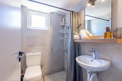 a bathroom with a sink and a toilet and a mirror at Aegean Sunset Luxury Penthouse in Lygaria