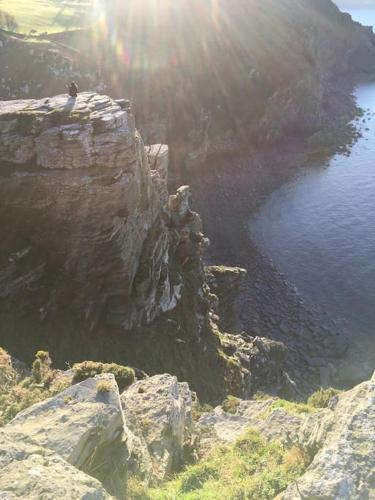 a person standing on top of a cliff near the water at Whitebeam, Moor and Sea Holidays, beautiful views over Exmoor in Lynton