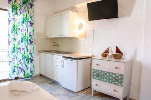 a kitchen with white cabinets and a tv on the wall at Brunis Apartments in Nei Poroi