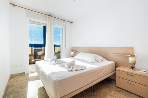 a white bedroom with a large bed and a window at Acintur 13-A Apartment Levante Beach-Old Town in Benidorm