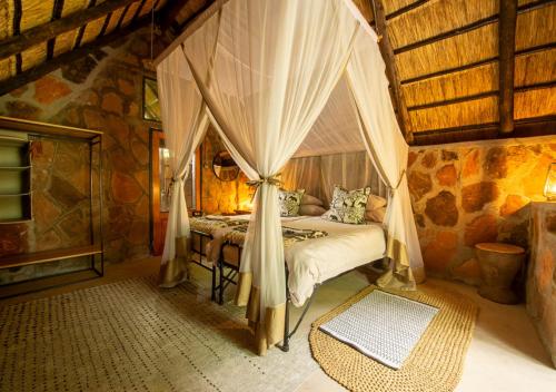 a bedroom with a bed with curtains in a room at Hideaways Bumbusi Wilderness Camp, Hwange in Hwange