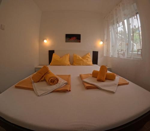 a bedroom with a bed with orange towels on it at Jadran Apartmani in Drage