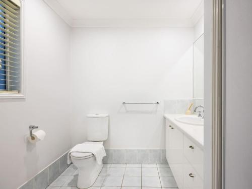 a white bathroom with a toilet and a sink at Private and Spacious 4BR Home with Parkview 5mins to Mall in Doolandella