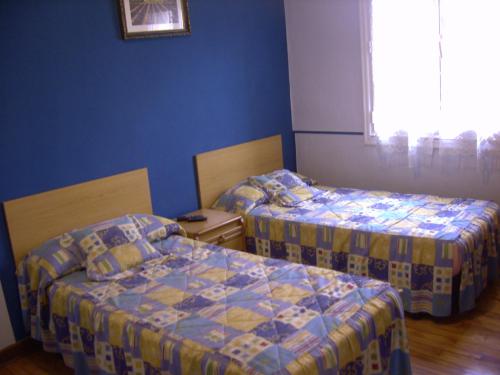 two beds in a room with blue walls at Pensión Gema in Irún