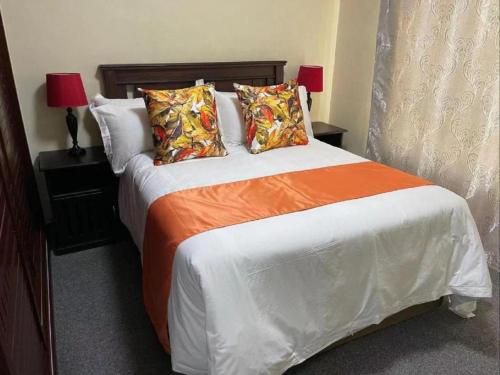 a bedroom with a bed with orange and white sheets and pillows at Lily Park Complex , Self-Catering in Rustenburg