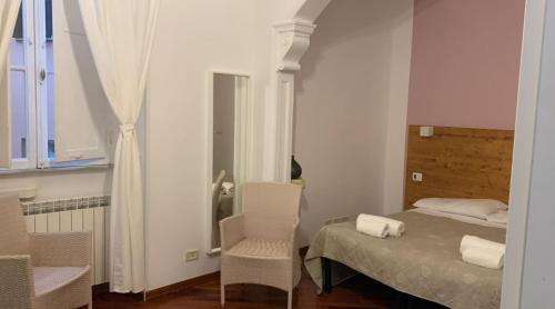 Un dormitorio con una cama y sillas y una ventana. en Domus Filiberto, en Roma