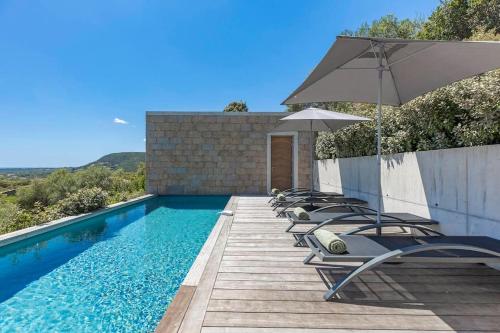 une piscine avec des chaises longues et un parasol dans l'établissement Villa A Grana, à Zonza
