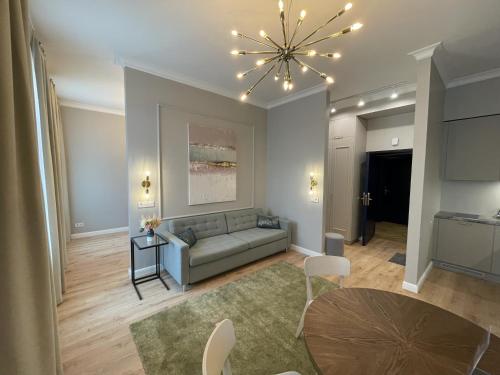 a living room with a couch and a chandelier at Aparthotel Amella in Rīga