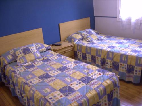 two beds in a room with blue walls at Pensión Gema in Irún