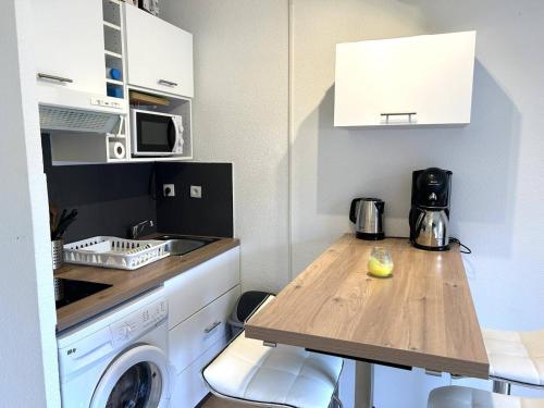 une cuisine avec une table et une machine à laver dans l'établissement Studio climatisé, 4 couchages, proche plage et commerces - Bormes-les-Mimosas - FR-1-251-737, à Bormes-les-Mimosas