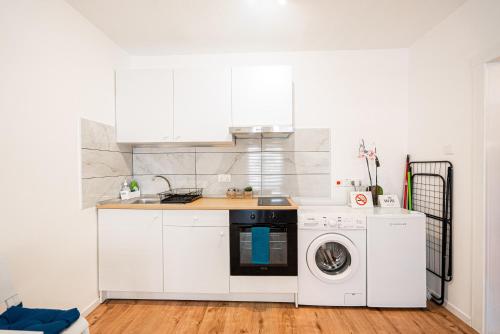 a kitchen with white cabinets and a washer and dryer at COZY Apartment In Kapparis #2 in Paralimni