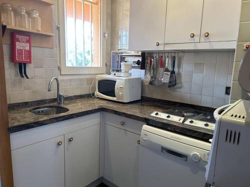 une cuisine avec un évier et un micro-ondes dans l'établissement Duplex climatisé avec 2 terrasses, garage, à 200m de la plage et proche commerces - Bormes-les-Mimosas - FR-1-251-733, à Bormes-les-Mimosas