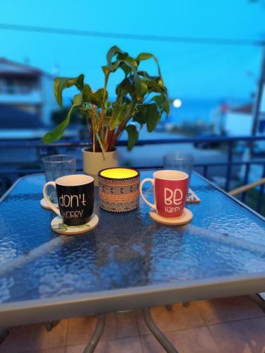 two coffee cups on a table with a potted plant at Mana mia Seaside Apartments in Leptokaria