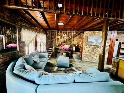 a living room with a blue couch and a brick wall at Zaganaga Kruger Lodge in Marloth Park