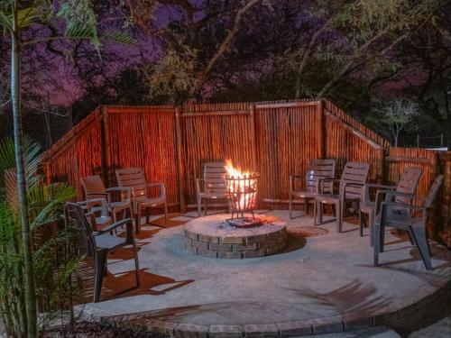 a fire pit in a yard with chairs and a fence at Zaganaga Kruger Lodge in Marloth Park