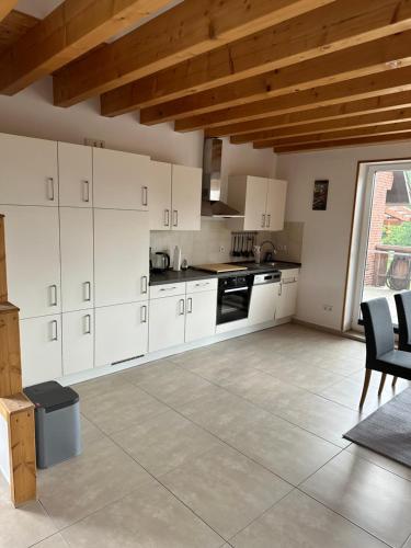 a kitchen with white cabinets and a table and chairs at Ferienhaus Fichtenschloss in Salzhausen