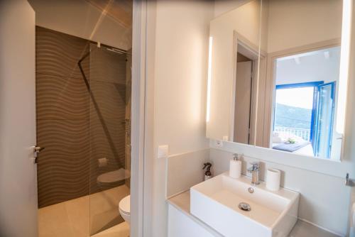 a white bathroom with a sink and a shower at ONIRO Villas in Stavros