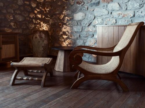 a chair and a stool in a room with a stone wall at KaSeas Boutique Hotel in Gerolimenas