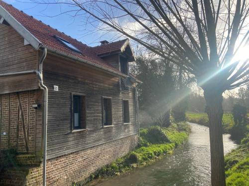 a building next to a river with the sun shining at Maison au bord de riviere , proche de la mer- spa semi rigide plein air en option in Bacqueville-en-Caux