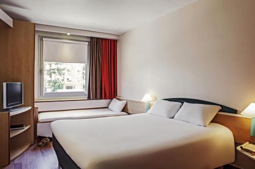 a hotel room with a large bed and a window at Ibis Barcelona Molins de Rei in Molins de Rei