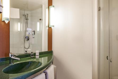 een badkamer met een groene wastafel en een spiegel bij Ibis Barcelona Molins de Rei in Molins de Rei
