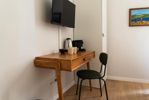 a desk with a chair and a television on a wall at Youhosty - Ticinese Suite 3 in Milan