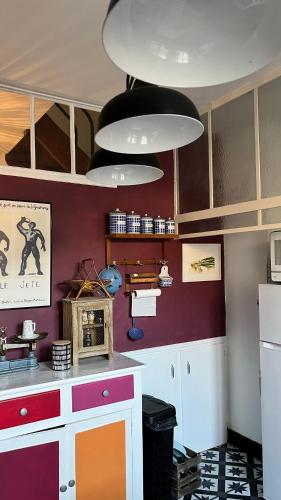 - une cuisine avec des murs violets et des placards blancs dans l'établissement Le Logis des Ais, à La Charité-sur-Loire