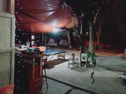 a tent with a table and a tree at night at JUNGLE GYM LA UNION Prana fan kubo 2 pax in Rimus