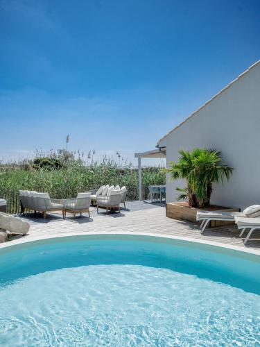une grande piscine avec des chaises et un patio dans l'établissement La Perle Rose Villa Standing 5 étoiles avec piscine jacuzzi et superbe vue, à Aigues-Mortes