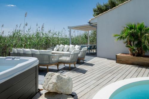 a patio with a table and chairs and a pool at La Perle Rose Villa Standing 5 étoiles avec piscine jacuzzi et superbe vue in Aigues-Mortes