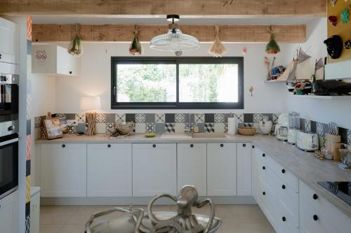 a kitchen with white cabinets and a window at La Perle Rose Villa Standing 5 étoiles avec piscine jacuzzi et superbe vue in Aigues-Mortes