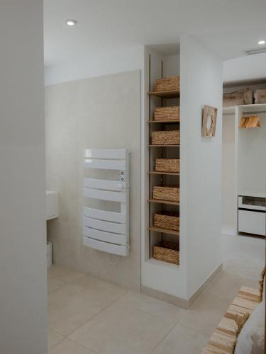 Cette chambre blanche dispose d'un placard avec du pain. dans l'établissement La Perle Rose Villa Standing 5 étoiles avec piscine jacuzzi et superbe vue, à Aigues-Mortes