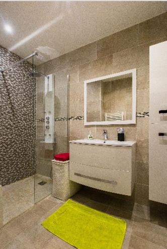 La salle de bains est pourvue d'un lavabo, d'une douche et d'un tapis jaune. dans l'établissement La Lanterne Plage, à Nice