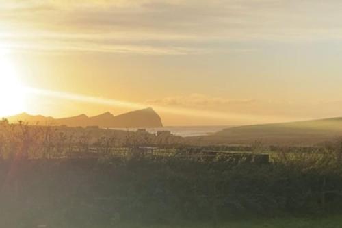 a view of a city with the sun in the background at An Riasc Farmhouse Rental in Dingle
