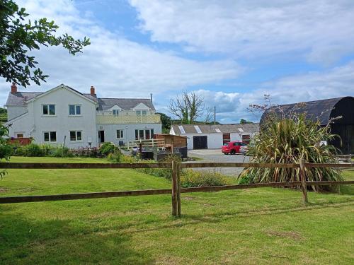 a wooden fence in front of a house at Bunny Meadows Holiday Farmhouse near Carmarthen & Pembrokeshire in Carmarthen